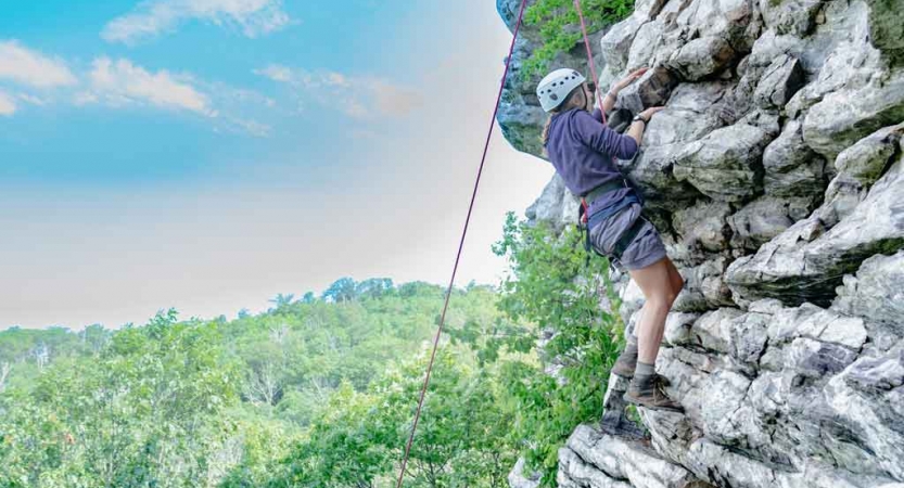girl rock climbs on outdoor expedition near baltimore
